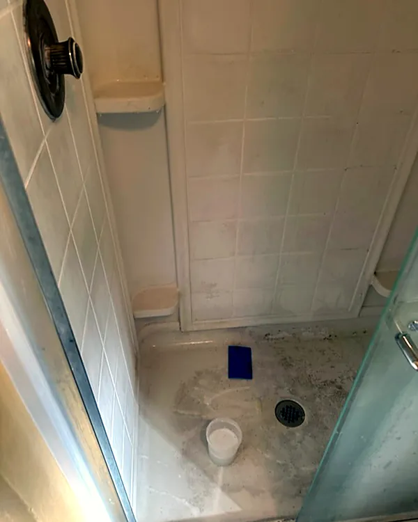 Shower floor and walls with soap scum and grime, before cleaning