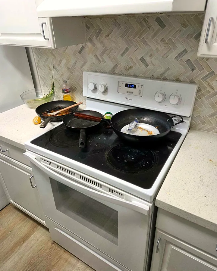 Stovetop covered in pans and spills, before cleaning