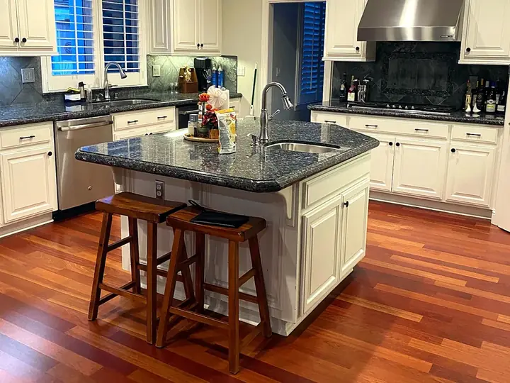 A clean kitchen with a cleared island and wood floors